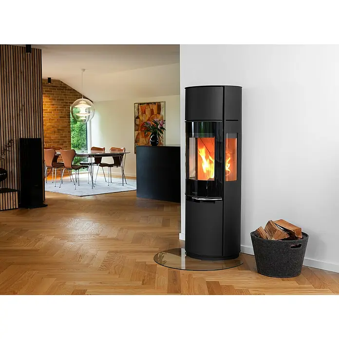 Aduro Kaminofen 9.7 Lux - 8 kW, Raumheizvermögen: 150 m³, Material Verkleidung: Stahl, Schwarz - Elegantes Interieur mit einem schwarzen Kaminofen, der Wärme und Stil in den Raum bringt. Ein gemütlicher Akzent mit einem Korb voller Holzscheite.
