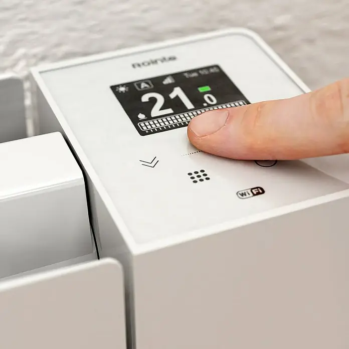 Rointe Emisor térmico Belize WiFi - 1.540 W, Blanco, 9,5 x 122 x 57,5 cm, Fluido - Primer plano de un termostato de radiador Rointe con un dedo en la pantalla táctil.