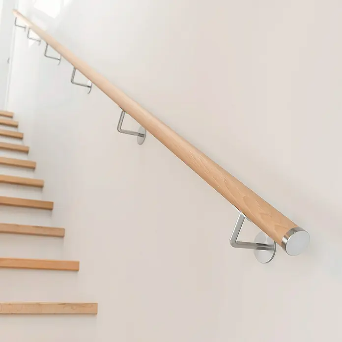 Dolle Wandhalter PS 911Edelstahl V2A, 2 Stk., Passend für: Dolle Holzhandläufe - Holzhandlauf mit Metallelementen an einer weißen Wand, der entlang einer Treppe verläuft. Er bietet Sicherheit und ist zugleich ein stilvolles Detail.