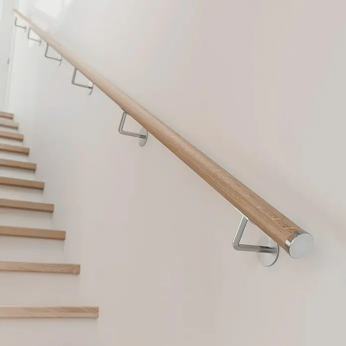 Dolle Handlauf PS 3/40 - Eiche Natur, Unbehandelt, Rund, Länge: 200 cm - Holzhandlauf mit Metallhalterungen an einer hellen Wand neben einer Treppe.