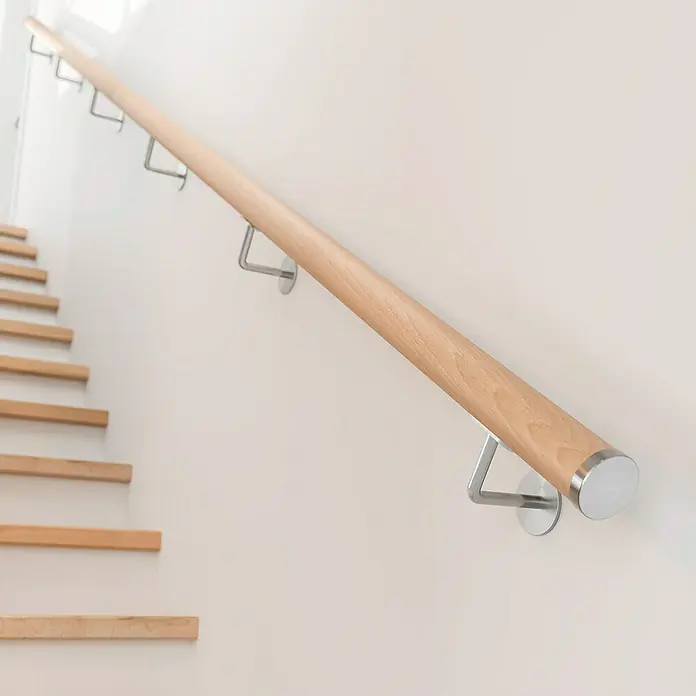 Dolle Handlauf PS 3/50 - Buche Natur, Unbehandelt, Rund, Länge: 200 cm - Nahaufnahme einer Holztreppe mit einem Holzhandlauf und Metallstützen an einer weißen Wand.