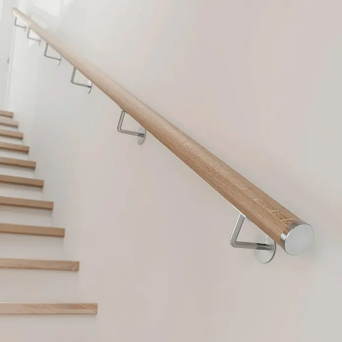 Dolle Handlauf PS 3/50 - Eiche Natur, Unbehandelt, Rund, Länge: 200 cm - Geländer aus Holz mit Metallbefestigungen an einer weißen Wand neben einer Holztreppe.
