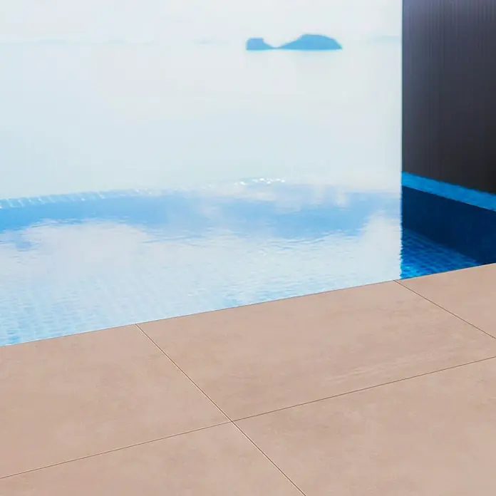 Terrassenfliese Modena - 80 x 80 x 2 cm, Taupe, Matt - Moderne Poolterrasse mit beigen Fliesen und Infinity-Pool, der einen nahtlosen Übergang zum Meer bietet, ideal für entspannende Momente im Freien.