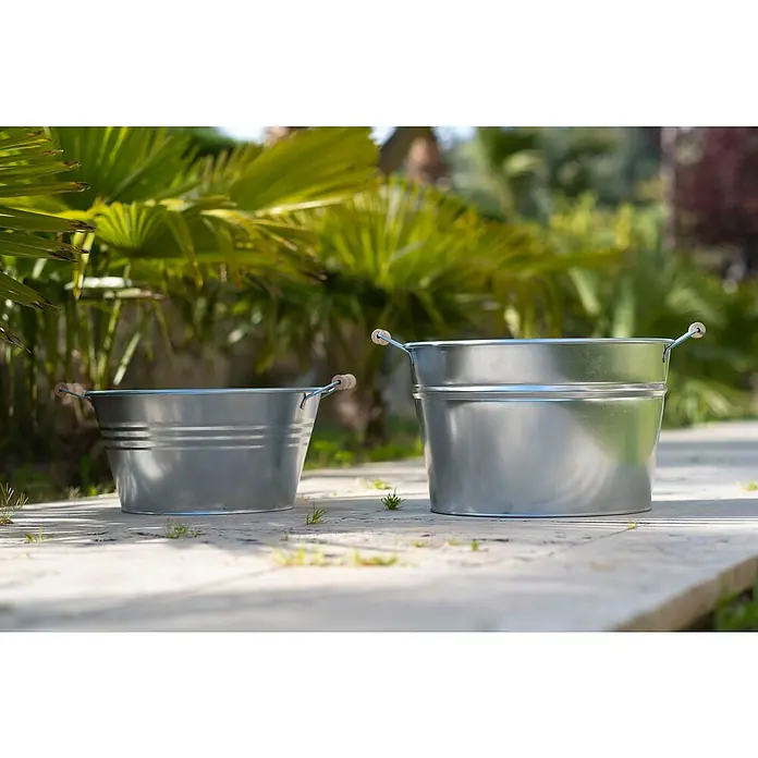 Zinkeimer - Metall, Ø x H: 36 x 25 cm - Zwei Metalleimer mit Holzgriffen stehen auf einer Terrasse, umgeben von üppigem Grün. Die Eimer sind ideal für Gartenarbeit oder Dekoration.