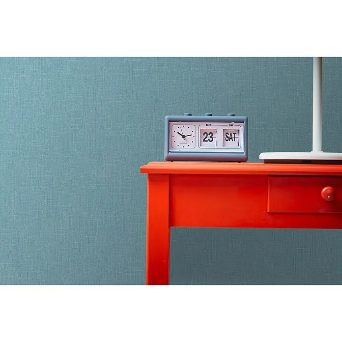 A.S. Création Metropolitan Stories Vliestapete Textil-Optik - Blau, Uni, 10,05 x 0,53 m - Der graue Schreibtischkalender mit analoger Uhr zeigt den 23. als Samstag an, und steht auf einem roten Tisch mit Schublade.