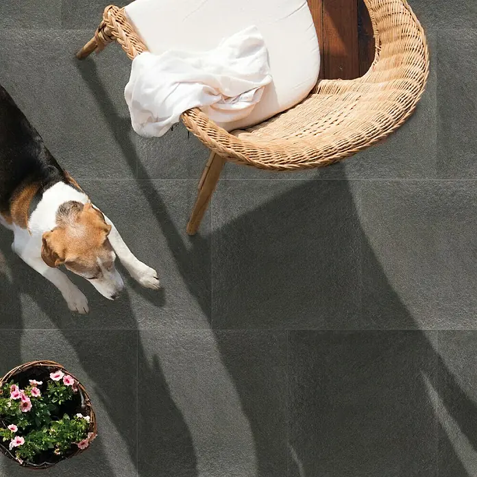 Terrassenfliese Manhattan 2.0 - 60 x 90 x 2 cm, Schwarz, Matt - Eine Nahaufnahme von Bodenfliesen im Außenbereich, die eine moderne und stilvolle Atmosphäre schaffen. Die Fliesen sind grau und haben eine feine Textur.