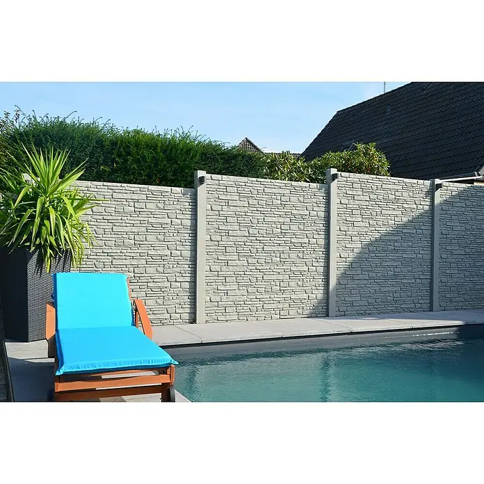 Beckers Betonzaun Zaunelement Standard Montana Motiv - 200 x 38,5 cm, Beton, Betongrau - Einladende Szene am Pool mit einem Liegestuhl mit türkisfarbener Auflage vor einer stilvollen Steinmauer und üppigem Grün.