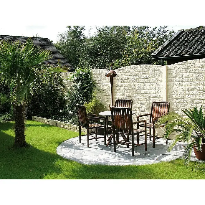 Beckers Betonzaun Abschlussplatte Standard Romaniabogen - 200 x 45 cm, Beton, Betongrau - Gartenmöbelset mit vier Stühlen und einem runden Tisch auf einer Steinterrasse, umgeben von üppigem Grün und einer hellen Mauer.