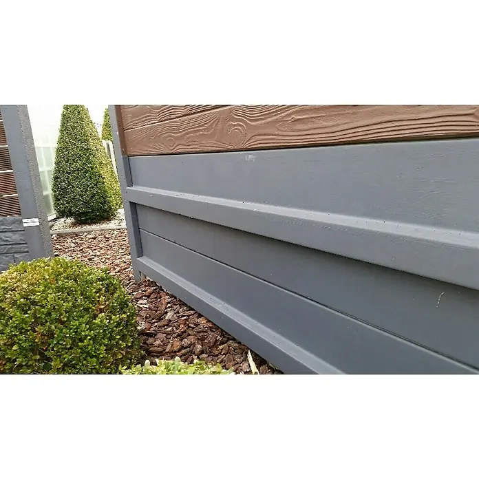 Beckers Betonzaun Zaunelement Standard Sockelplatte - 200 x 38,5 cm, Beton, Betongrau - Detailaufnahme eines modernen Gartenzauns mit Holz- und grauen Kunststoffelementen, umgeben von gepflegten Pflanzen und Rindenmulch.