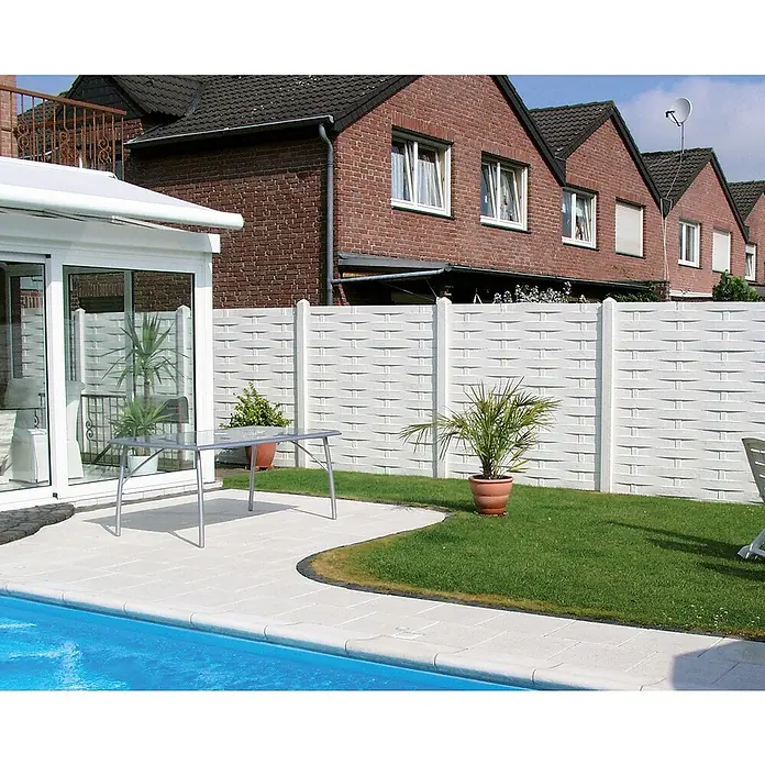 Beckers Betonzaun Zaunelement Standard Flecht Motiv - 200 x 38,5 cm, Beton, Betongrau - Blick auf einen Garten mit einem Pool und einem weißen Zaun. Der Zaun bietet Privatsphäre und fügt sich gut in die grüne Umgebung ein.