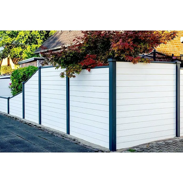 Beckers Betonzaun Zaunelement Klassik Solide Motiv - 184 x 26 cm, Beton, Betongrau - Eine weiße Holzzaunstruktur mit grauen Pfosten umrandet ein Grundstück mit Bäumen und Pflanzen. Der Zaun bietet Privatsphäre und Schutz.