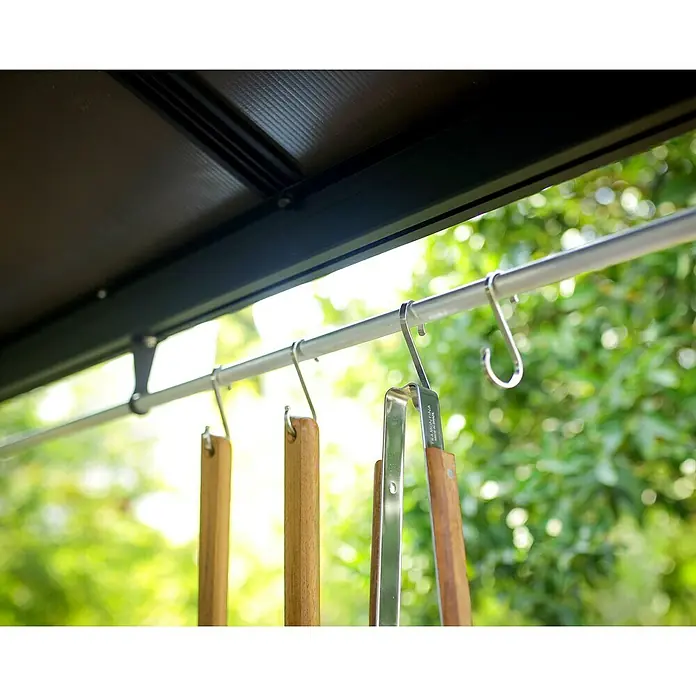 Palram – Canopia Pérgola para barbacoa Austin - An x Pr: 240 x 180 cm, Color del armazón: Antracita, Aluminio - Primer plano de utensilios para asar con mangos de madera colgados de una barra, sobre un fondo borroso.