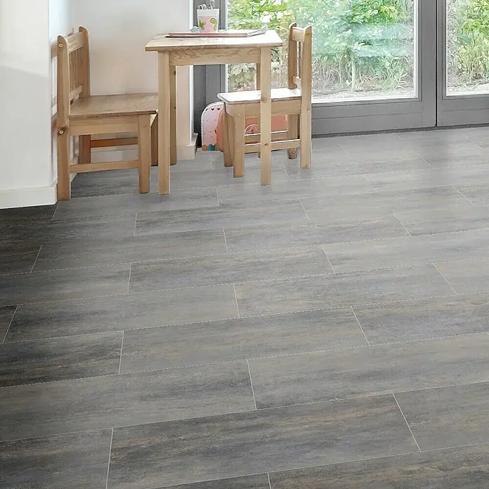 Feinsteinzeugfliese Allora - 30 x 60,4 cm, Schwarz, Matt - Detailaufnahme des Bodens mit länglichen, grauen Fliesen, die wie Holz aussehen, in einem hellen Raum mit Kindermöbeln.