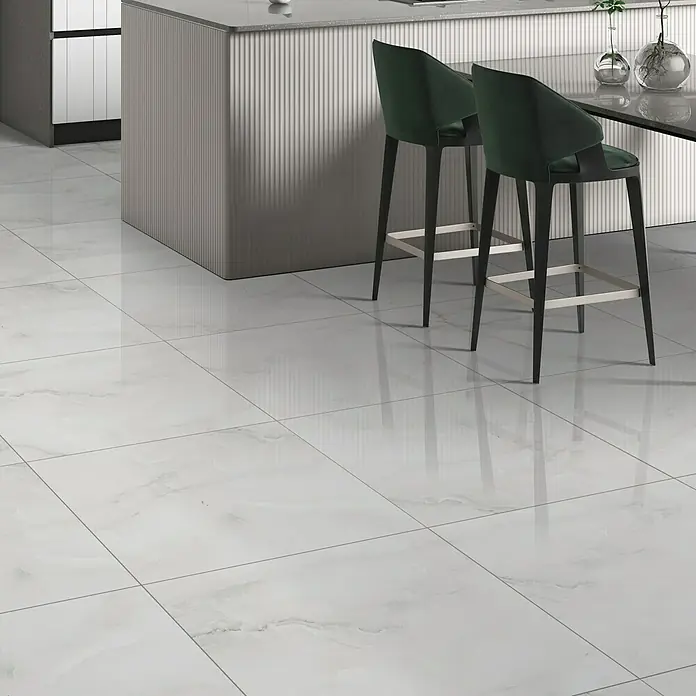 Feinsteinzeugfliese Royal Onyx - 60 x 60 cm, Hellgrau, Glänzend - Elegante weiße Marmorfliesen mit dezenten Maserungen bedecken den Boden, ergänzt durch moderne Barhocker und eine stilvolle Kücheninsel.