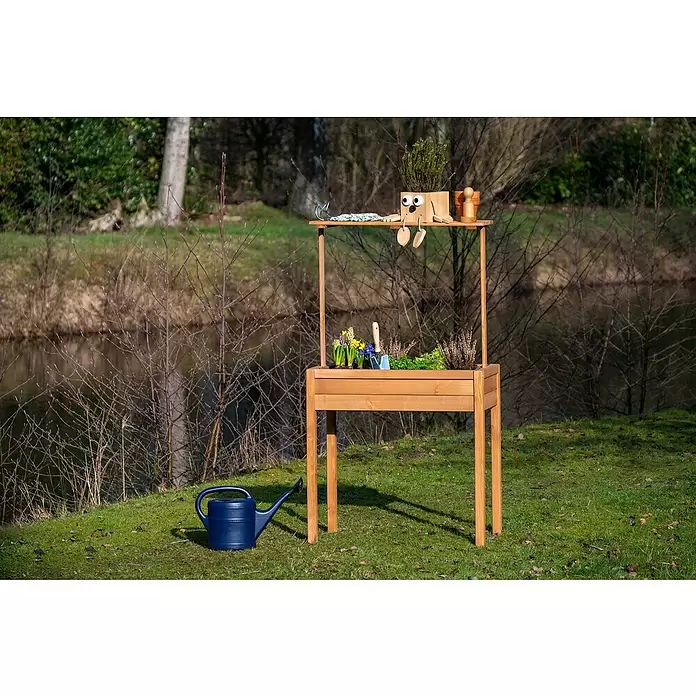 Dobar Hochbeet - 80 x 40 x 145 cm, Holz, Braun - Hölzernes Hochbeet/Pflanztisch mit zwei Etagen, bepflanzt und mit Gartengeräten, daneben eine blaue Gießkanne.