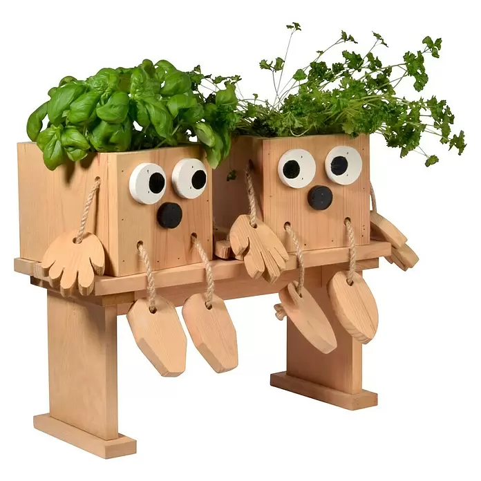 Dobar Pflanztopf Kräuterschwestern Laura & Lisa - Holz, Braun - Zwei helle Holz-Pflanztöpfe, als sitzende Figuren auf einer Bank geformt, mit frischem Basilikum und Petersilie.
