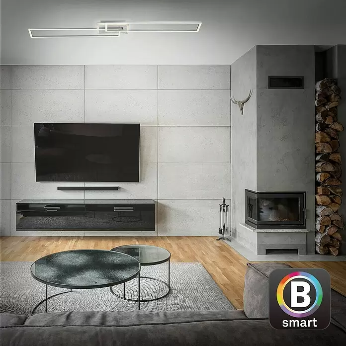 Brilo LED-Wand- & Deckenleuchte Frame S - 34 W, L x B x H: 110 x 24,8 x 7,8 cm, Aluminiumfarbig, Warmweiß - Moderne lineare LED-Deckenleuchte mit geometrischem Design beleuchtet ein Wohnzimmer.