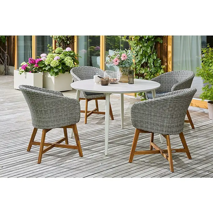 Sunfun Gartenmöbel-Set Solo/Pauline - 5 -tlg., Aluminium/Sintered Stone/Akazie/Polyrattan, Light-Greige//Bambus Grey/Natur - Ein runder Gartentisch mit vier Rattanstühlen auf einer Holzterrasse, umgeben von Blumen und Grünpflanzen.