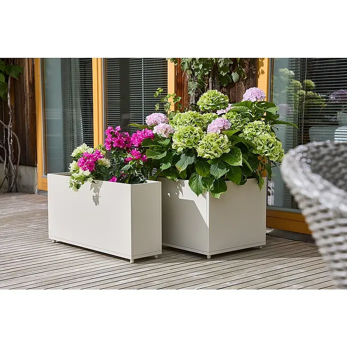 Sunfun Lumar Pflanzkübel eckig - Außenmaß (L x B x H): 89 x 23 x 45 cm, Stahl, Light-Greige - Zwei bepflanzte, moderne Pflanzgefäße in Weiß mit bunten Blumen und grünen Pflanzen auf einer Holzterrasse, die eine stilvolle Gartengestaltung ermöglichen.