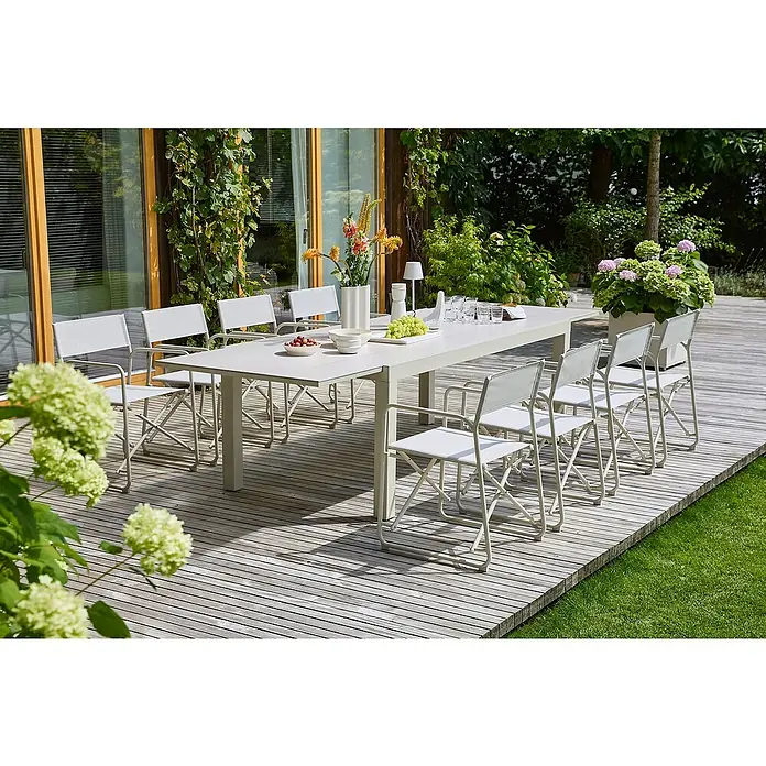 Sunfun Gartenmöbel-Set Maja/Sarah - 9 -tlg., Light-Greige, Ausziehbar - Elegantes Outdoor-Esstischset mit passenden Stühlen auf einer Holzterrasse, umgeben von üppigem Grün. Perfekt für Mahlzeiten im Freien.