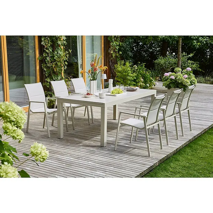 Sunfun Gartenmöbel-Set Maja - 7 -tlg., Light-Greige, Ausziehbar, Tisch (Lx B x H): 200-300 x 100 x 74 cm, Stuhl (B x T x H): 56,5 x 66 x 91 cm - Ein grauer Gartentisch mit passenden Stühlen auf einer Holzterrasse, dekoriert mit Blumen und Geschirr, lädt zum Verweilen im Freien ein.