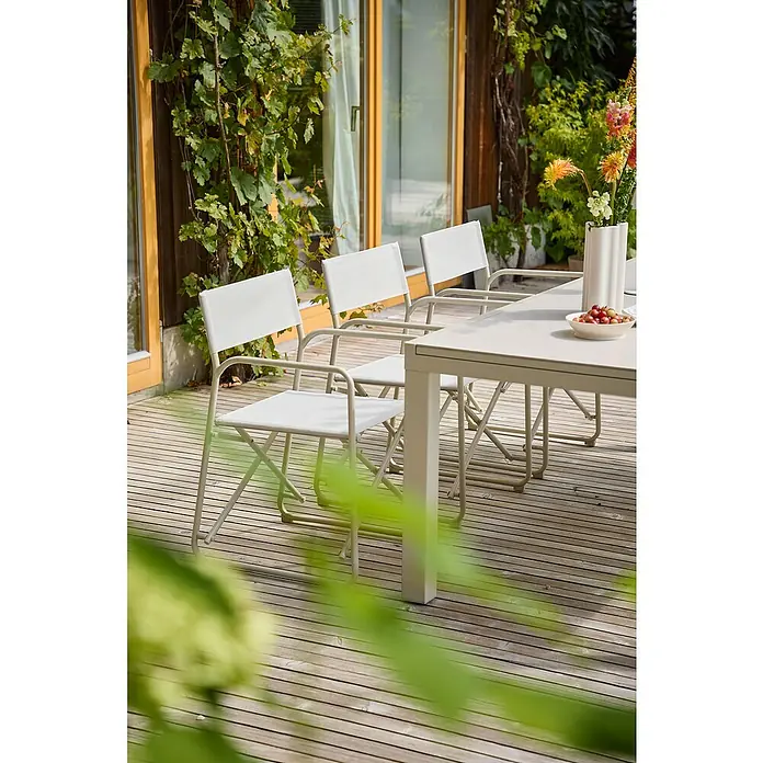 Sunfun Sarah Gartenstuhl - Aluminium, Textil, Klappbar, Light-Greige, B x T x H: 56 x 52,5 x 81 cm - Eine Nahaufnahme von drei hellen Outdoor-Stühlen aus Stoff und Metall an einem passenden Tisch auf einer Holzterrasse, umgeben von Grün.