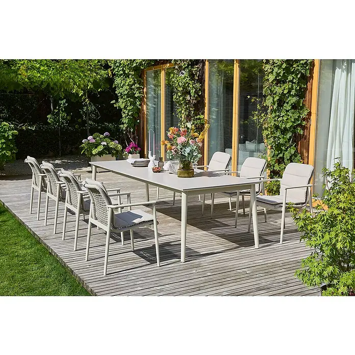 Sunfun Gartenmöbel-Set Solo Rope - 17 -tlg., Aluminium/Sintered Stone/Kunststoff/Olefin, Light-Greige, Ausziehbar - Elegantes Gartenmöbel-Set mit Esstisch und Stühlen auf einer Holzterrasse, umgeben von üppigem Grün, ideal für Mahlzeiten im Freien.