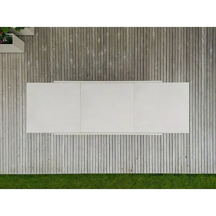 Sunfun Maja Gartentisch Stone - L x B x H: 300 x 100 x 74 cm, Aluminium, Sintered Stone, Ausziehbar, Light-Greige - Draufsicht auf einen stilvollen, weißen Gartentisch auf einer Holzterrasse mit grüner Rasenkante. Ideal für Mahlzeiten im Freien.