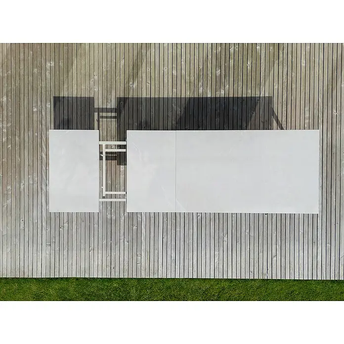 Sunfun Gartenmöbel-Set Solo/Sarah - 12 -tlg., Aluminium/Sintered Stone/Textilen, Light-Greige, Ausziehbar - Ein ausziehbarer Gartentisch aus hellem Holz und Metall auf einer Holzterrasse mit Rasen im Hintergrund.