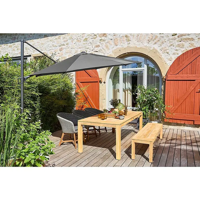 Sunfun Gartenmöbel-Set Laura/Pauline/Capri - 6 -tlg., Braun/Grau - Eine stilvolle Gartentischgruppe mit Sonnenschirm auf einer Holzterrasse vor einem Steinhaus. Perfekt für entspannte Stunden im Freien.