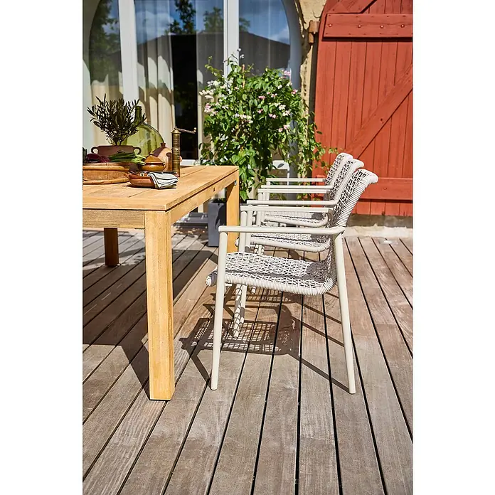 Gartenmöbel-Set Laura/Solo/Capri - 8 -tlg., Braun/Leight-Greige, Stapelbar - Ein Außenbereich mit einem Holztisch und mehreren Flechtstühlen, die einladend und stilvoll wirken.