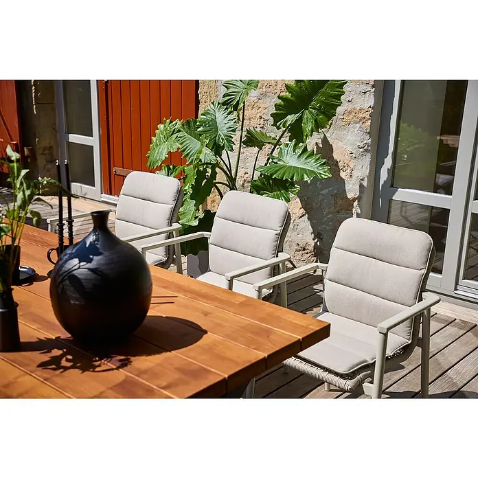 Sunfun Solo Rope Niederlehner-Auflage - Passend für: Sunfun Solo Gartensessel, Olefin, Light-Greige - Einladender Außenbereich mit einem Holztisch, drei bequemen Stühlen mit Polsterung und einer stilvollen schwarzen Vase als Dekoration.