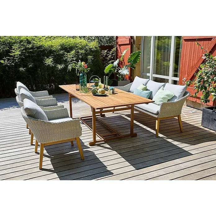 Sunfun Diana Gartentisch - L x B x H: 180 x 100 x 75 cm, Akazie, Naturbraun, Ausziehbar - Holztisch-Garnitur mit Rattansesseln und Bank mit Polsterauflagen auf einer Holzterrasse, umgeben von Grünpflanzen für den Außenbereich.