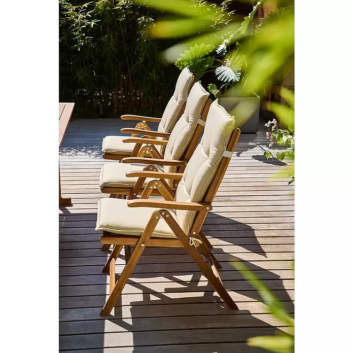 Doppler Gartenmöbel-Auflage Passion - Beige, L x B x H: 119 x 48 x 6 cm - Drei Holz-Gartenstühle mit cremefarbenen Kissen auf einer sonnigen Holzterrasse.