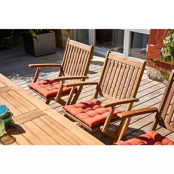 Sunfun Sitzkissen Nils - L x B x H: 40 x 40 x 4 cm, Terracotta, 100% Polyester - Hölzerne Outdoor-Essgarnitur mit Stühlen und Tisch, orangefarbene Sitzkissen auf einer sonnigen Holzterrasse.
