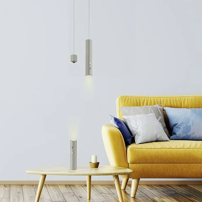 Just Light Lámpara colgante de batería Attach - Gris - Interior elegante con iluminación moderna: una lámpara de mesa y dos colgantes iluminan la sala de estar con sofá amarillo.