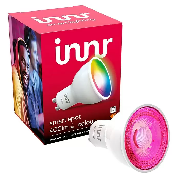 Innr Lighting Smart-LED-Lampe Spot Colour - GU10, Dimmbar, RGBW, 400 lm, 4,8 W, 1 Stk. - Weißer smarter GU10 LED-Strahler mit farbigem Licht, neben der pinken Markenverpackung.