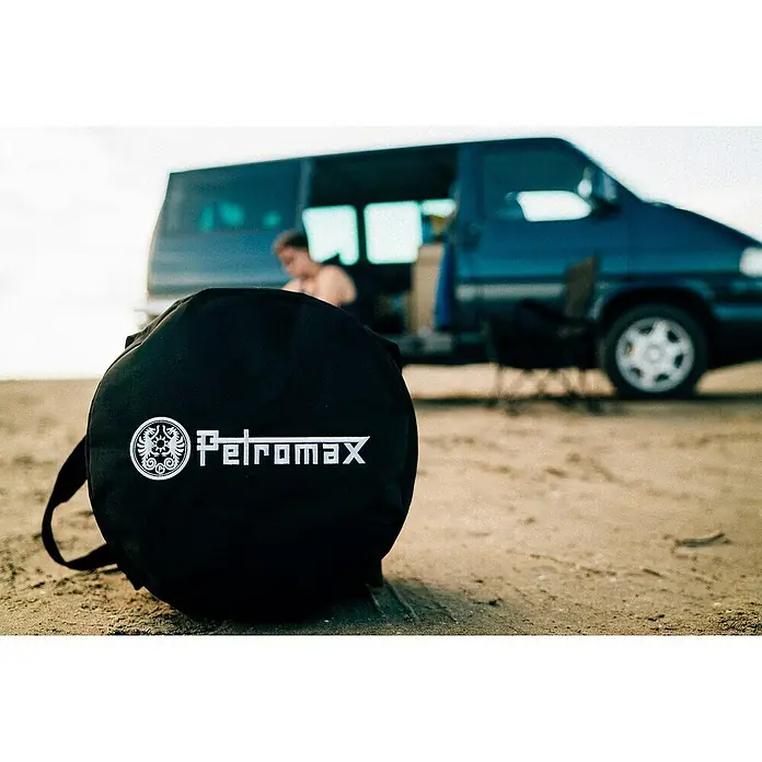 Petromax Transporttasche FT 6 & FT 9 - Ø x H: 40 x 24 cm, Polyester - Nahaufnahme einer schwarzen Petromax-Tasche vor einem Van, die Outdoor-Abenteuer verspricht.