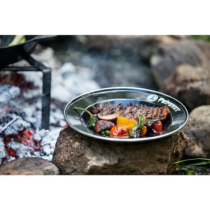 Petromax Teller rund - Ø x H: 22,5 x 2,5 cm, Schwarz, Stahl, 2 Stk. - Gegrilltes Steak und Gemüse auf einem Petromax Teller, serviert auf einem Stein neben einem Lagerfeuer.