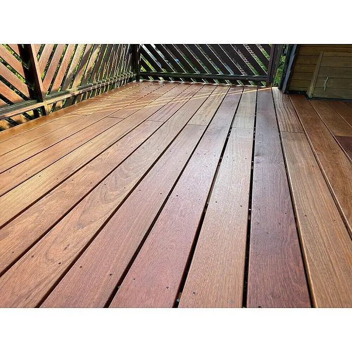 Terrassendiele - 244 x 14,5 x 2,1 cm, Braun - Eine Nahaufnahme eines Holzdecks mit geraden Linien und Schrauben, die die Holzplanken verbinden, wobei ein Geländer im Hintergrund sichtbar ist.