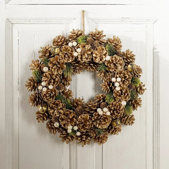 Dekokranz Tannenzapfen - 35 cm, Braun - Ein goldener Zapfenkranz mit weißen Beeren und kleinen Glocken hängt an einer weißen Holztür, der festlichen Deko für Weihnachten.