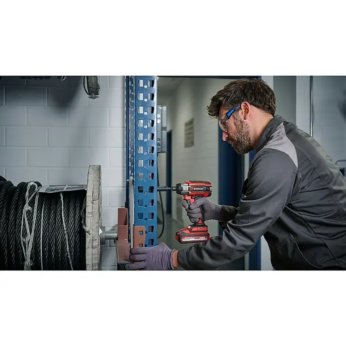 Einhell Professional Power X-Change 18V Akku-Schlagschrauber TP-CI 18/220 LI BL - 18 V, Ohne Akku, 220 Nm - Ein Mann arbeitet mit einem Einhell Akku-Schlagschrauber an einem Regal. Der Schrauber ist rot-schwarz und kabellos.