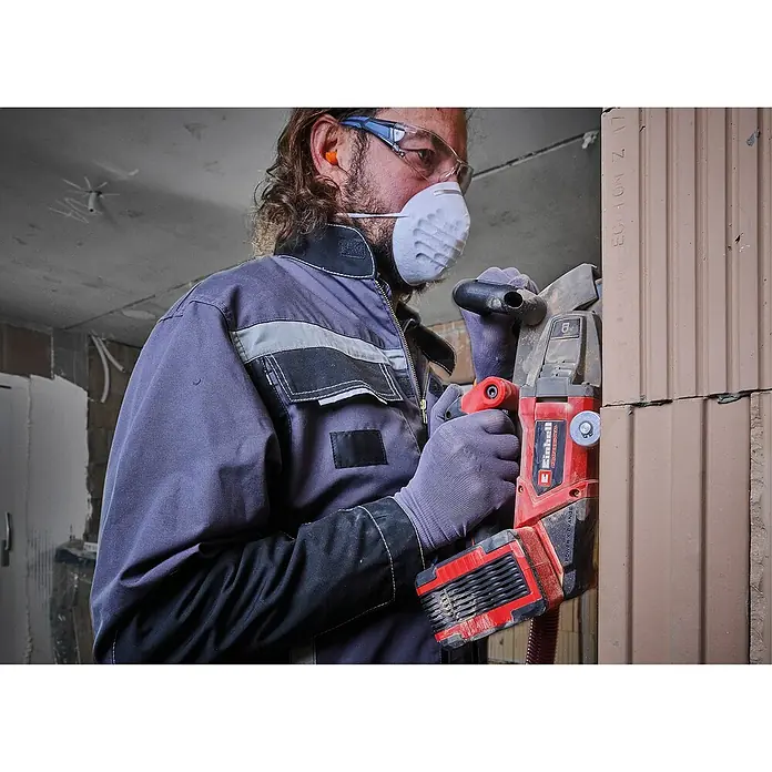 Einhell Professional Power X-Change 18V Akku-Mauernutfräse - 18 V, Ohne Akku, 0 Ah, Durchmesser Schleifscheibe: 125 mm - Bauarbeiter mit Einhell Mauernutfräse beim Schneiden von Schlitzen in eine Ziegelwand, Schutzmaske und Brille tragend.