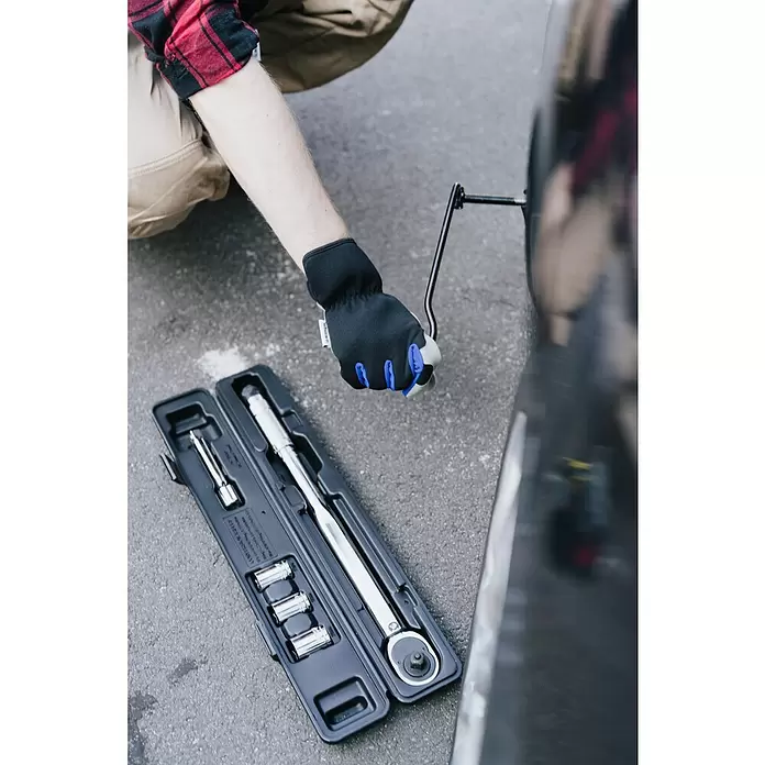 Wisent Arbeitshandschuhe - Handschuhgröße: 8, Grau/Schwarz - Behandschuhte Hand bedient einen Wagenheber am Auto. Ein offener schwarzer Koffer mit silbernem Drehmomentschlüssel und Nüssen liegt auf Asphalt.