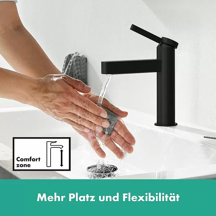 Hansgrohe Finoris Waschtischarmatur 110 - Schwarz, Push-Open-Ablaufgarnitur - Matter schwarzer Waschtischmischer in Gebrauch, Wasser läuft über Hände im weißen Waschbecken, betont Platz und Flexibilität.