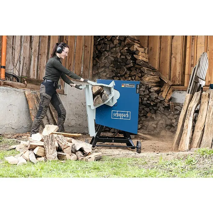 Scheppach Wippkreissäge HS720 - 4.500 W, Durchmesser Sägeblatt: 700 mm - Eine Frau benutzt eine Scheppach Wippsäge zum Schneiden von Holzscheiten. Die Säge ist blau und steht auf einem Untergestell mit Rädern.