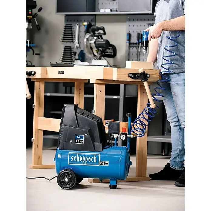 Scheppach Kompressor HC30o - Max. Druck: 8 bar, 24 l - Werkstatt-Szene mit einem blauen Scheppach Luftkompressor im Vordergrund, der für Druckluftwerkzeuge verwendet wird.