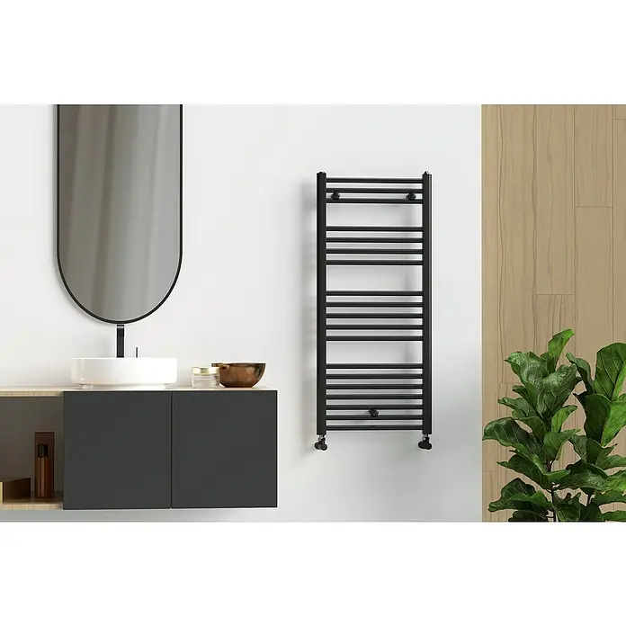 Rointe Radiador toallero Elba Aqua - An x Al: 50 x 112 cm, 459 W, Negro - Un baño moderno con un toallero negro montado en la pared, junto a un tocador con espejo y una planta.