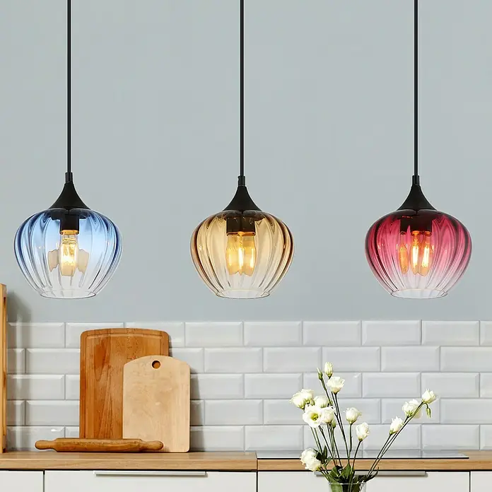 Globo LED-Pendelleuchte Sander - 60 W, L x B x H: 80 x 18 x 150 cm, Amber, Blau, Rot, Schwarz matt - Drei bunte Glaspendelleuchten über einer Küchenzeile mit Holzakzenten und weißen Fliesen.