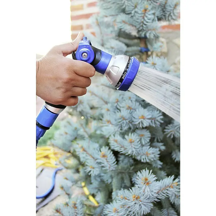 Kit de manguera helicoidal + soporte - Largo: 10 m - Se está utilizando un pulverizador de jardín azul para regar un árbol, el agua sale a presión por la boquilla.